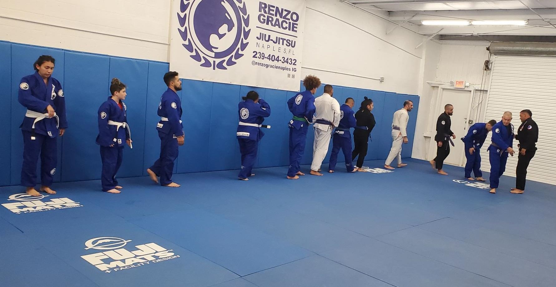 Renzo Gracie Naples members in their gis on the mat in front of the academy wall